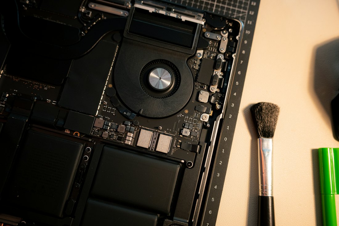 PC portable ouvert en cours de nettoyage, avec un pinceau